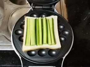 这是电铛板做的：在鸡蛋仔电铛机上放一片吐司，再放入青瓜条（或生菜）