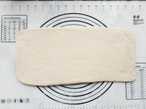 将面团倒在操作台上，稍整理并擀成长方形。