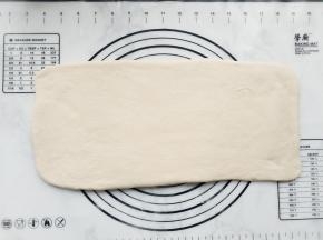 将面团倒在操作台上，稍整理并擀成长方形。