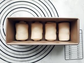 依次卷好所有面团，放入模具中。每个吐司盒中放入4个面团。