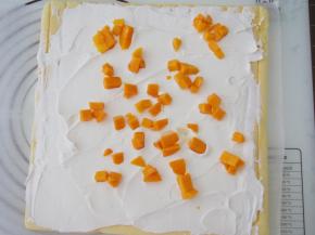 淡奶油加糖打发好，将蛋糕片翻转过来放到油纸上，均匀抹上一层淡奶油，再铺上一层芒果粒