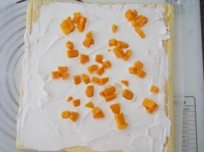 淡奶油加糖打发好，将蛋糕片翻转过来放到油纸上，均匀抹上一层淡奶油，再铺上一层芒果粒