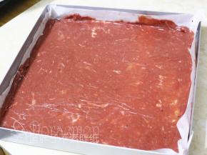 在烤盘上平铺一张油纸，取200g肉糜平铺在油纸上，表面盖上保鲜膜，将肉糜擀成均匀的薄薄的一片。