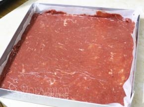 在烤盘上平铺一张油纸，取200g肉糜平铺在油纸上，表面盖上保鲜膜，将肉糜擀成均匀的薄薄的一片。