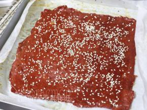 8分钟后取出肉脯，继续两面刷上蜂蜜，表面撒上白芝麻，送入烤箱 180度，烘6分钟。