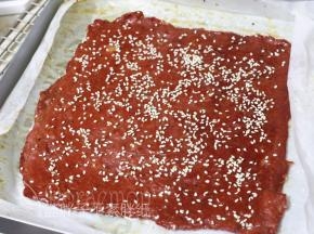 8分钟后取出肉脯，继续两面刷上蜂蜜，表面撒上白芝麻，送入烤箱 180度，烘6分钟。