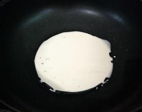 舀一汤勺的面糊倒入抹油的锅中，把锅子转动，将其均匀的铺上一层