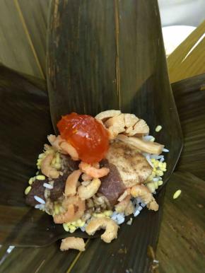 先放一点糯米，然后把馅料放入。最后再铺一层糯米，我要四张竹叶才包好一个粽子哦。