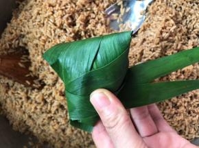 随着粽叶翻卷过来，就可以包住整个粽子了
