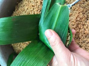 把多余的粽叶翻盖住糯米