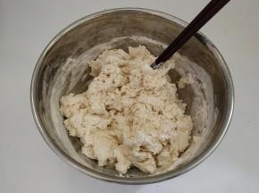 把面团用料倒入碗中混合以后，然后再加入温水，用筷子挑成絮状。
