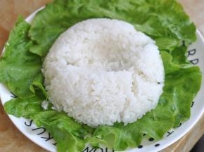 盘子里铺上生菜，将米饭倒扣在盘中，中间压出一个坑。