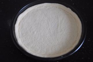 披萨盘抹上少许的橄榄油，把面胚放进披萨盘内，用叉子插出孔，防止烤制的时候鼓起来