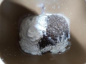 面包机先放入鸡蛋和清水，再放入盐、高筋面粉和全麦粉，挖个洞放入酵母，加入炒香的奇亚籽，启动揉面程序15分钟。