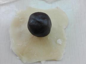 将卷过两次的面团，两头向中间捏一下，按扁，擀成中间厚，四周薄的圆片，放入事先准备好的馅料