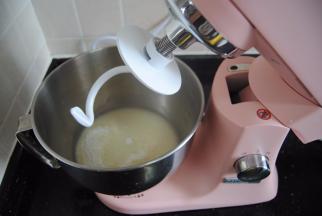 按下厨师机机头的银色按钮，抬起厨师机头，装上揉面勾，把揉面团放入卡口卡紧