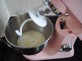 按下厨师机机头的银色按钮，抬起厨师机头，装上揉面勾，把揉面团放入卡口卡紧