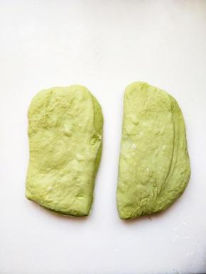将面团拿到工作台，用刮刀切成两等份，面团表面推展开来，搓成圆形，以湿布覆盖在上面让面团静止十分钟