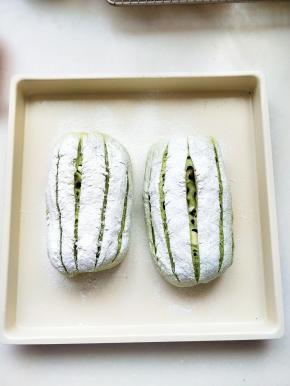 .将整形好的面包放置在烤盘上进行二次发酵，放置在温暖处直到膨胀1.5倍到2倍，使用滤网撒上高粉，以刀在面团上划五刀直线