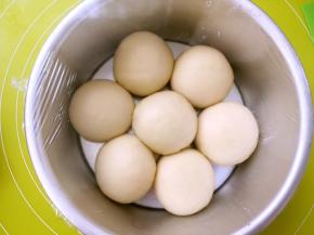 全部包裹好后，将奶酪包放入模具内，如图外圈6个，中间一个的摆放，盖保鲜膜室温发酵至两倍大，因为奶酪馅是冰箱冷冻的，在包裹好后，内馅降低了面团的温度，发酵的时间比较慢，没关系，慢慢等待就行