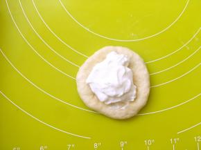 之后将面团翻过来，将光滑的一面朝下，这样包好的奶酪面包表面就是光滑的，之后冰箱取出冷冻的奶酪馅，放在面团中间，一点点捏紧收口