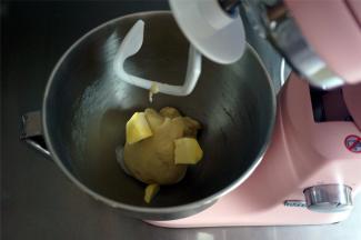 加入面团配方中的盐和黄油，用2档低速和面2分钟至完全融合。