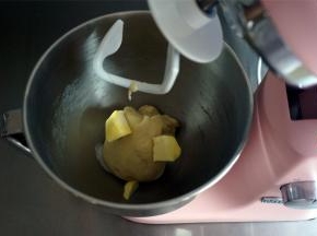 加入面团配方中的盐和黄油，用2档低速和面2分钟至完全融合。