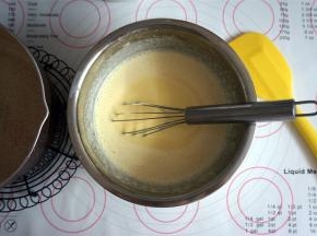 将煮过的糖牛奶慢慢加入到蛋黄糊中，边倒边搅拌。