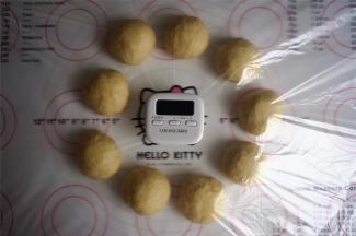 将面团倒出至案板上，用手轻压，排出大气泡，然后分割成9个50克左右的面团，滚圆，盖上保鲜膜，松弛15分钟。