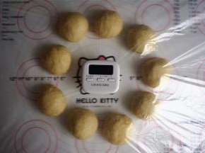 将面团倒出至案板上，用手轻压，排出大气泡，然后分割成9个50克左右的面团，滚圆，盖上保鲜膜，松弛15分钟。