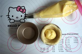 将圆形面片放入不粘蛋挞模中，挤入适量的卡仕达奶油，将收口捏紧，收口朝下重新放入蛋挞模具中，依次将其余面团做好。