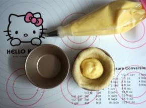 将圆形面片放入不粘蛋挞模中，挤入适量的卡仕达奶油，将收口捏紧，收口朝下重新放入蛋挞模具中，依次将其余面团做好。