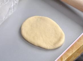 取一个面团，压扁，擀成牛舌状。