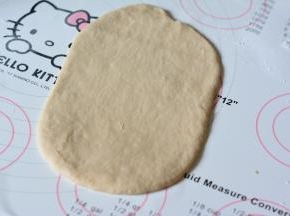 取一份面团擀成椭圆形，稍微用手压一下边缘，尽量排出多余的气体一面做出来的面包组织不够好，一端稍微擀的薄一些。