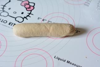 沿短边卷起梭子形，收紧两端。