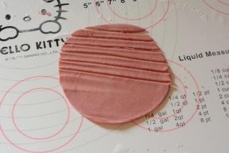 剩下的面团取少量加入少许红曲粉揉至成团，擀成薄片。切成长条做小熊围巾待用。