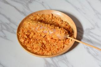 然后将香肠沾满薯片碎，烤箱预热200度。