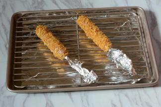 在烤盘内垫上一层锡箔纸，将烤肠放在烤架上。