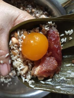 填入一半混合好的馅料，加放入咸蛋黄、腊肠、猪肉，接着再填满馅料