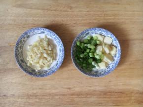 准备两小碟的佐料，左边的是蒜蓉，一部分用于炒熟菜以后放入的，一部分用于撒在餐盘里的，右边的是炝锅用的葱花和蒜片。
