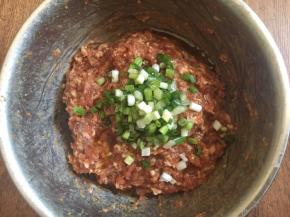 放入葱花，在葱花上淋上1小勺香油，用香油裹住葱花，锁住葱汁，然后再朝一个方向继续搅拌均匀。