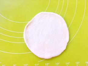 取一份松弛好的白色面团，用擀面杖擀成圆片