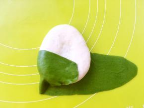 先将一侧的抹茶面片掀起来，包裹在白色面团上