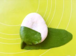 先将一侧的抹茶面片掀起来，包裹在白色面团上