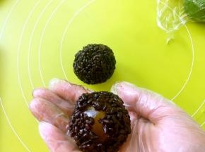 手上戴一次性手套，将紫米饭压扁，包裹上咸蛋黄