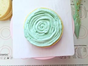 19、取一片蛋糕放在裱花台上，奶酪霜装入裱花袋剪一个小口，画圈方式挤上一层奶酪霜。