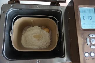 倒入奶粉和面粉，在面粉顶端加入酵母，面包桶放入到东菱1352AE-3C面包机里，选择和面10分钟（不同型号的面包机和面时间和方法不同，时间仅供参考）