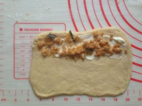 松驰后的面团擀成长方形，一端抹上沙拉酱，撒上肉松