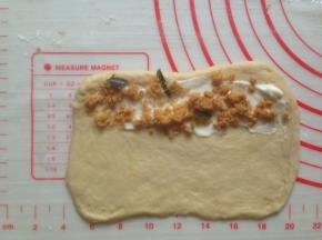 松驰后的面团擀成长方形，一端抹上沙拉酱，撒上肉松