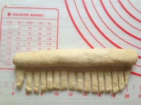 从上往下卷到剩余1/3，用刮面刀切成若干细长条